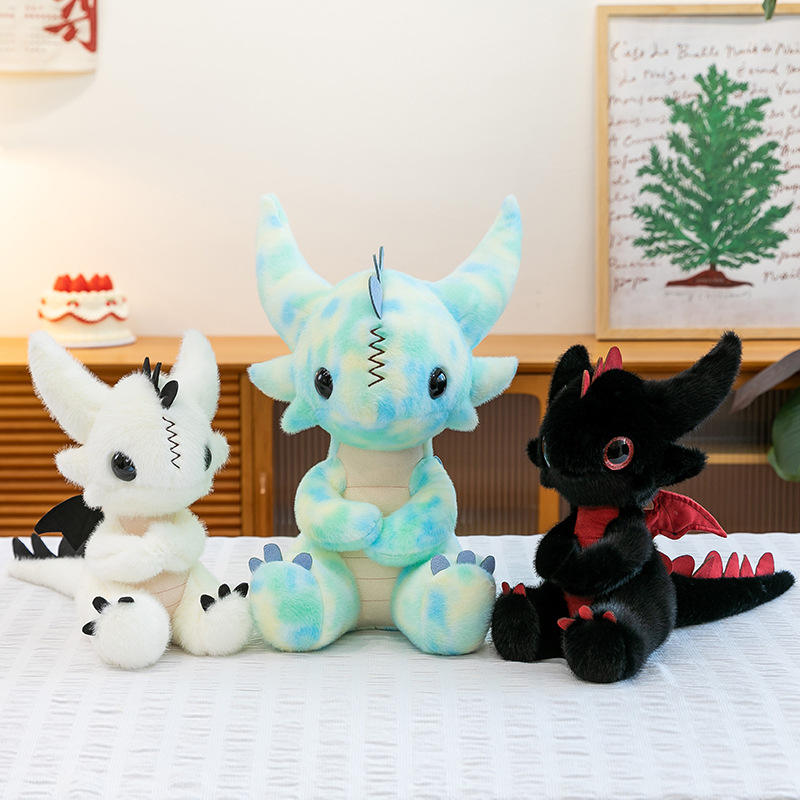 A group of three cute dragon plushies in light blue marble, solid white, and black colors sitting on a table.